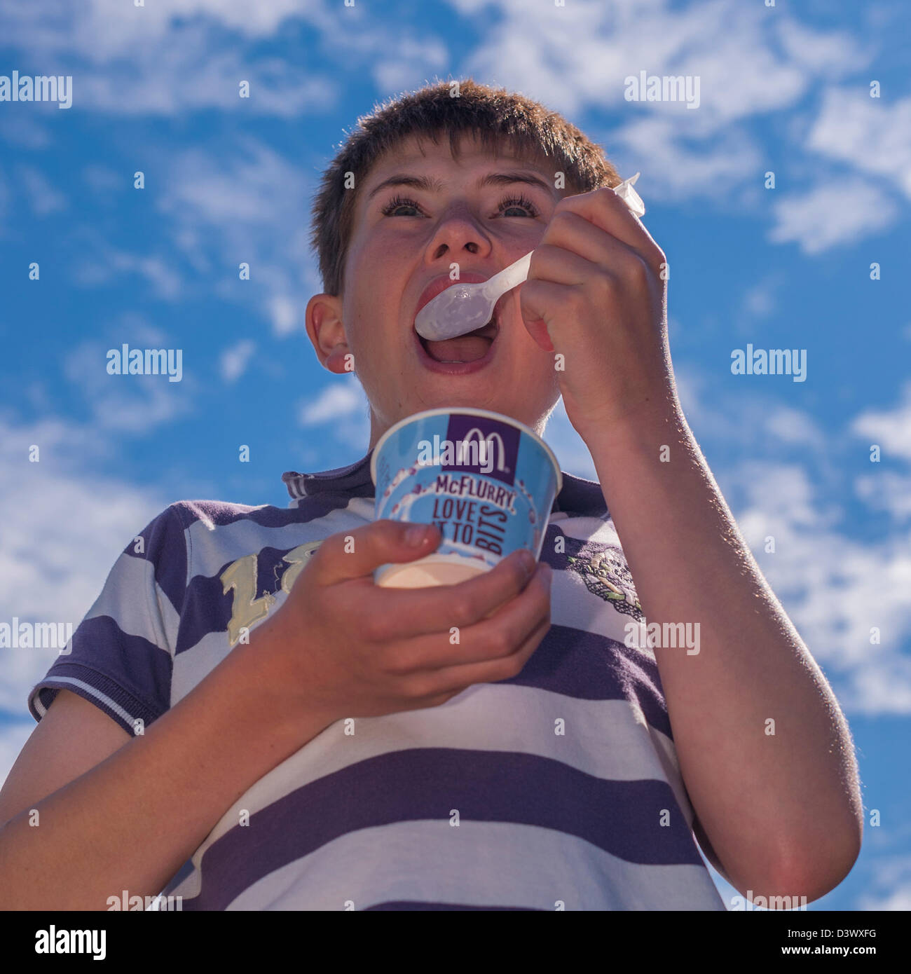 A 12 year old boy eating a mcdonalds Mcflurry ice cream outdoors in the uk Stock Photo