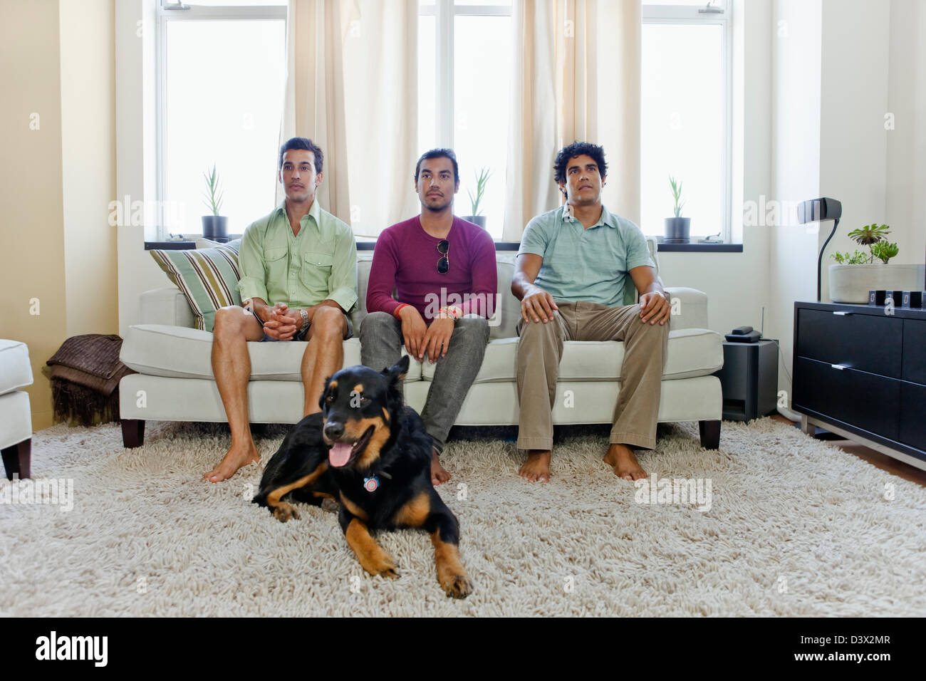 Young Hispanic-American Men, Sitting in Living Room Waiting, Bored Stock Photo