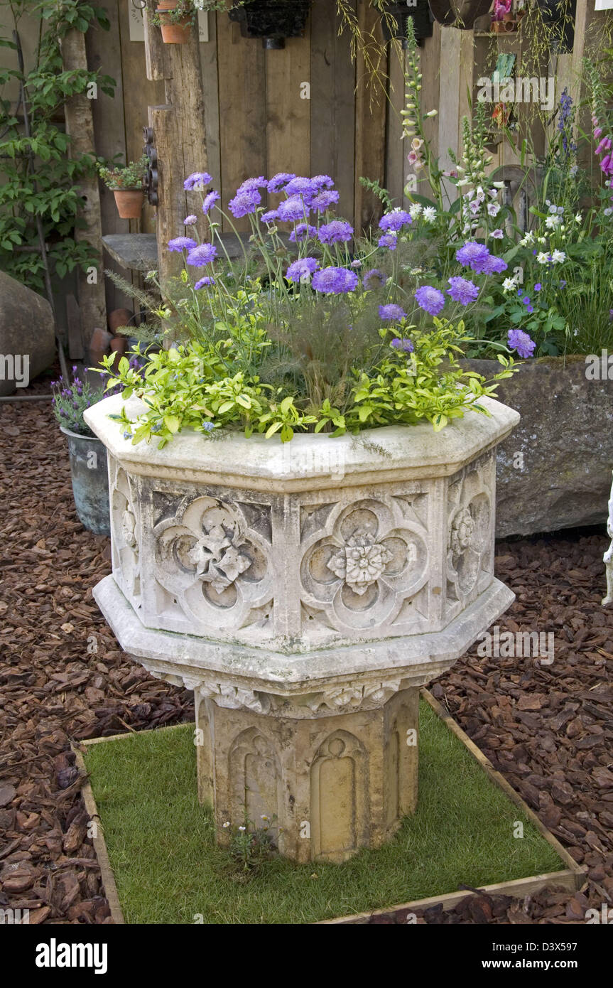 Stone font with ornate ecclesiastical carving used as a planter. Exhibited at Chelsea 2008 by J's Pots and Potted Plants. Stock Photo