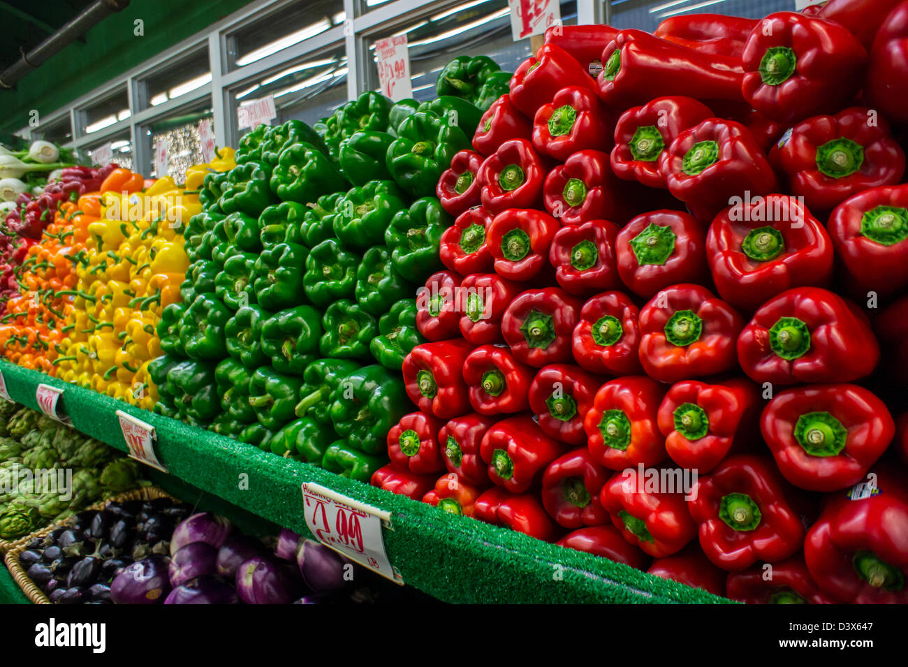 Red, green, yellow and orange peppers and other vegetables are seen on sale in a grocery store in New York Stock Photo