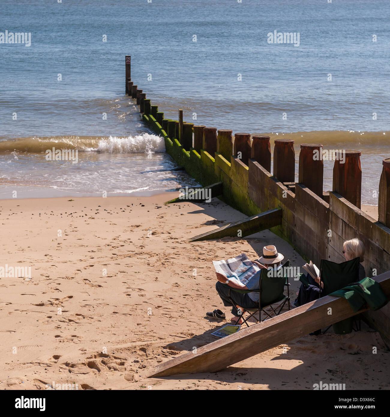 A couple reading on the beach at Southwold , Suffolk , England , Britain , Uk Stock Photo