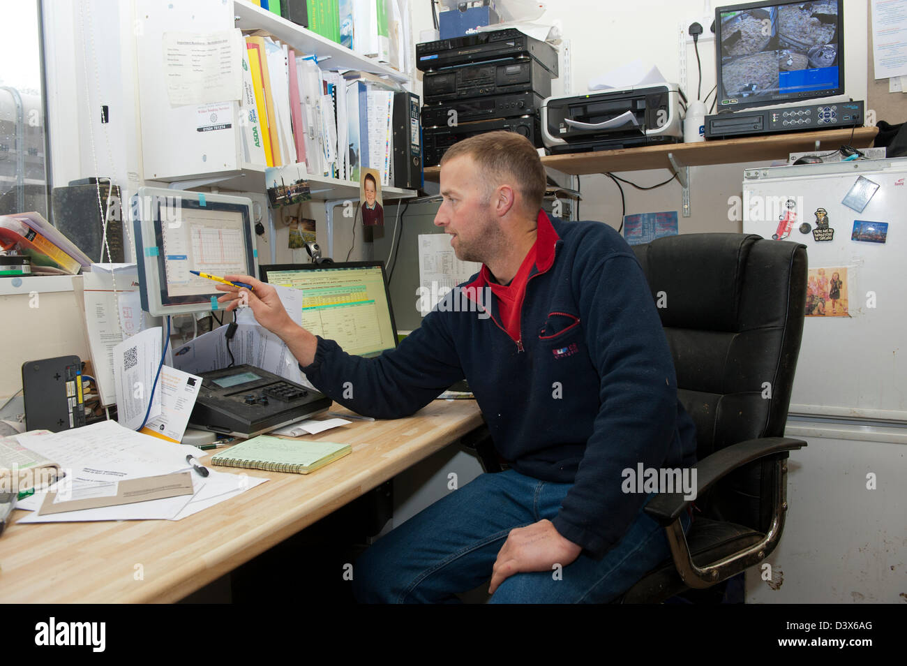 Farmer looking at computer in farm office Stock Photo Alamy
