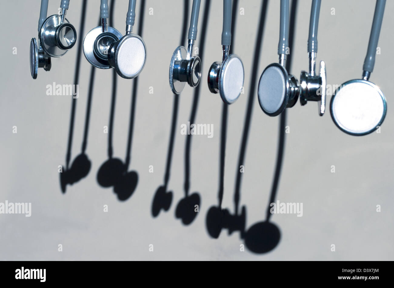Row of stethoscopes and shadows against a gray background Stock Photo