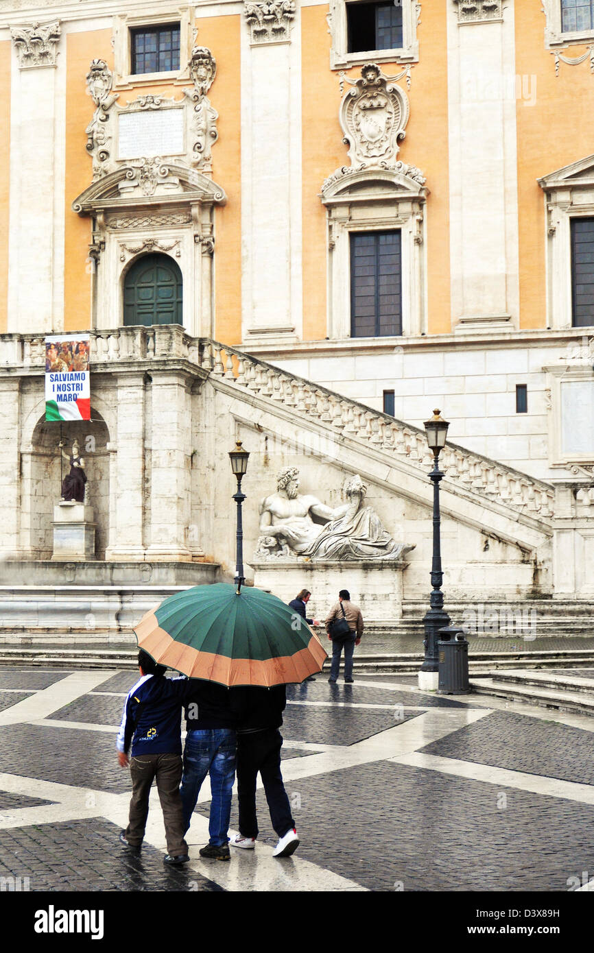 Three boys shelter under one umbrella, Capitoline Hill, Rome, Italy Stock Photo