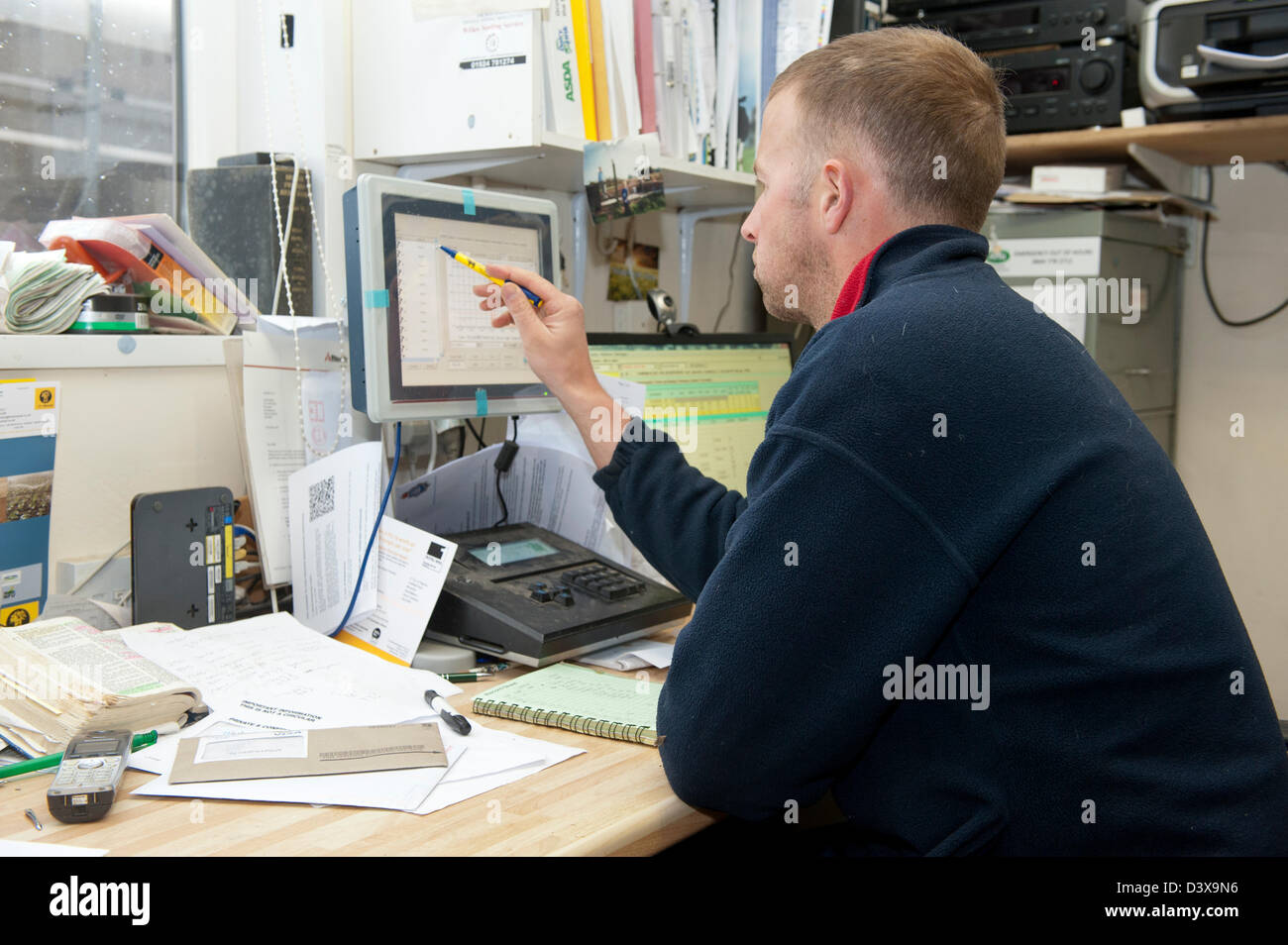 Farmer looking at computer in farm office Stock Photo Alamy