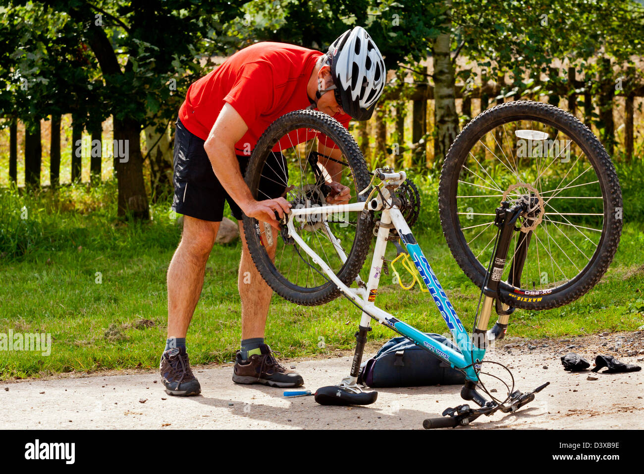 Man in red shirt changing back wheel and repairing puncture on mountain bike Stock Photo Alamy
