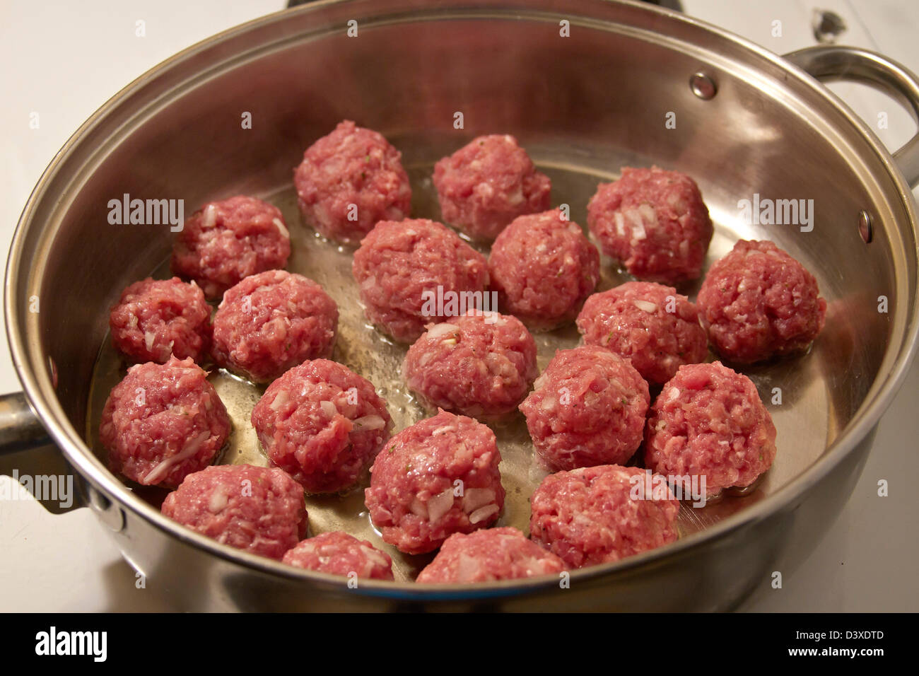 Meatballs being cooked in a frying pan with oil Stock Photo