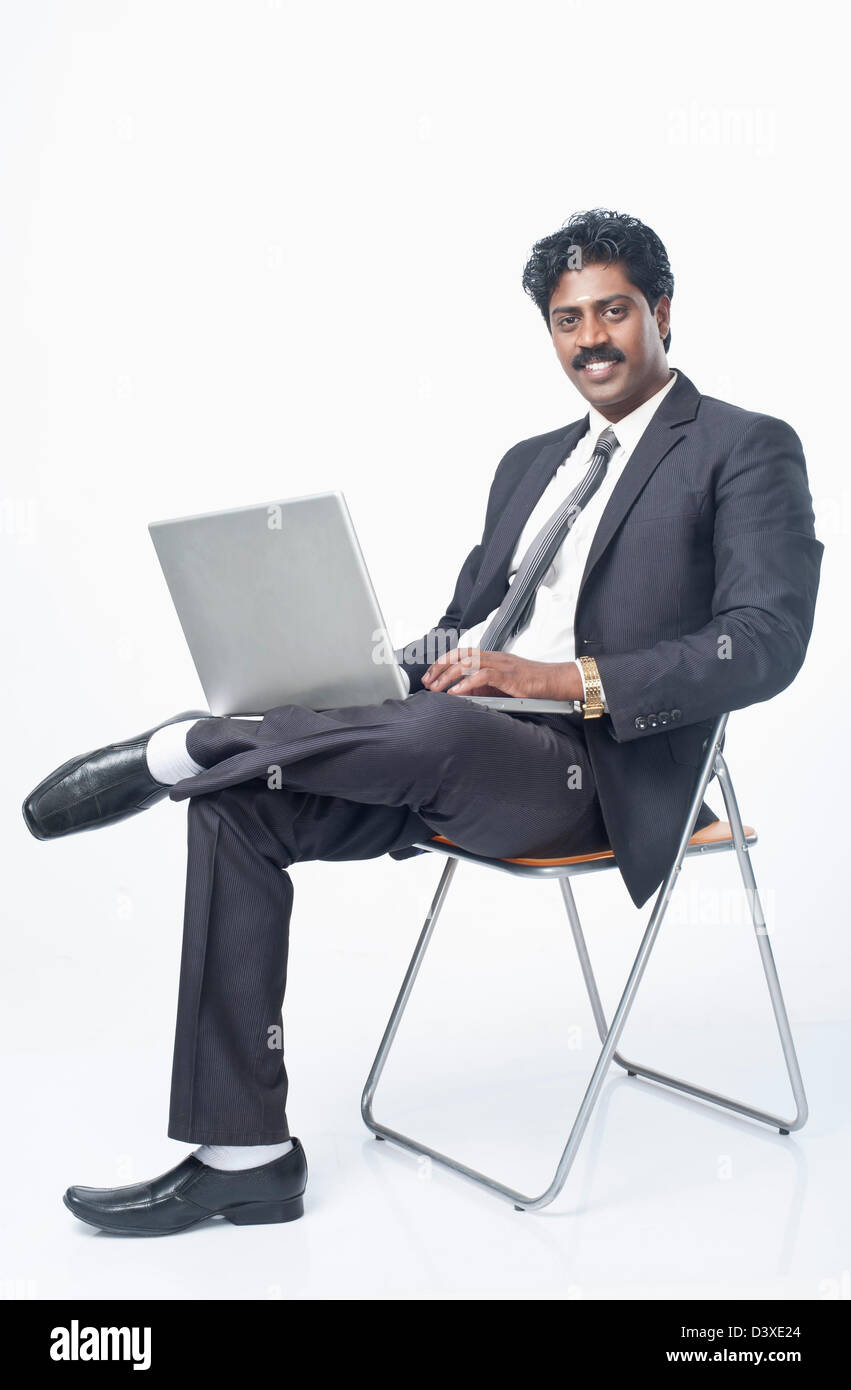 South Indian businessman sitting on a chair and using a laptop Stock ...