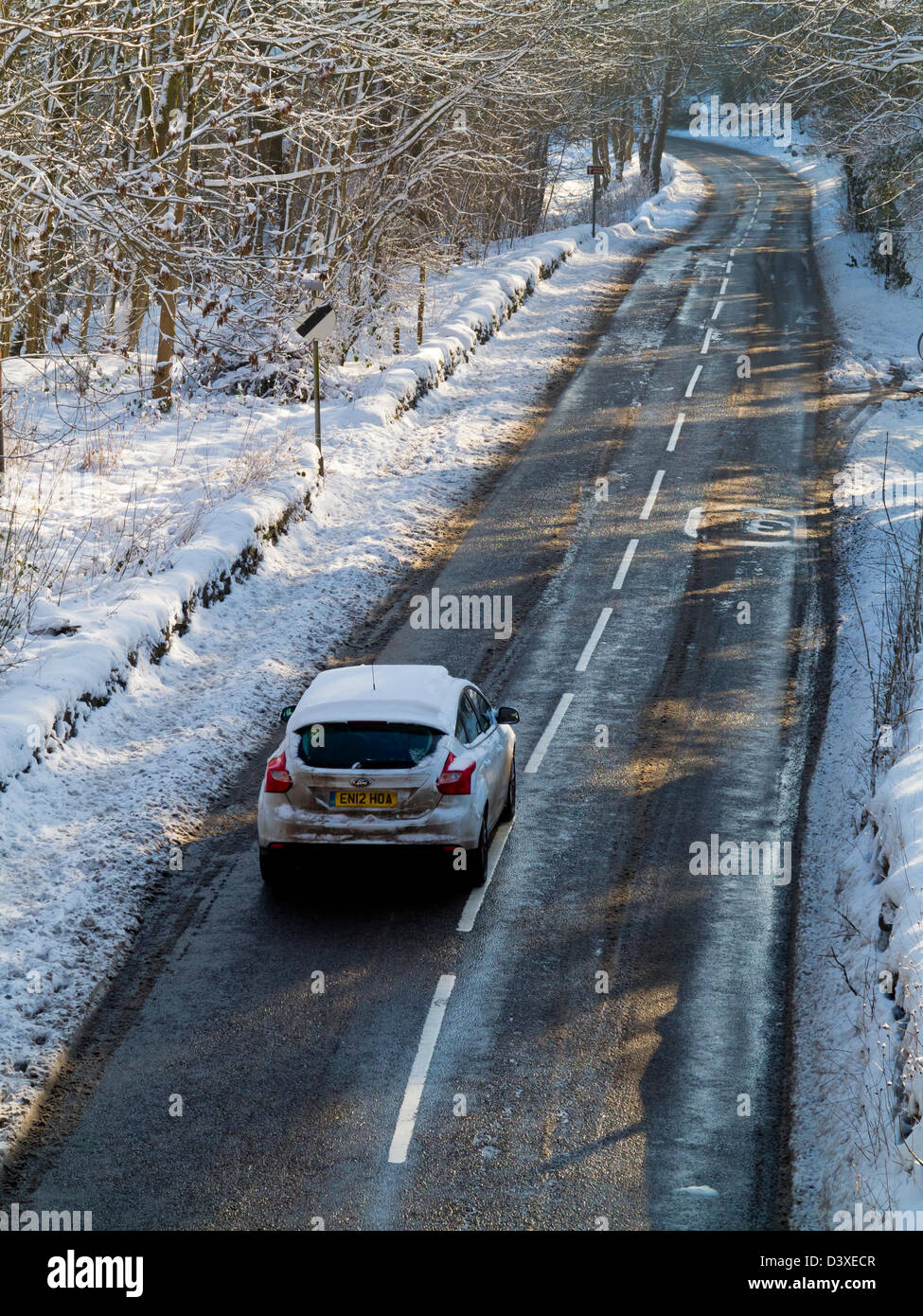 Car driving down icy road in winter after recent heavy snow Wirksworth