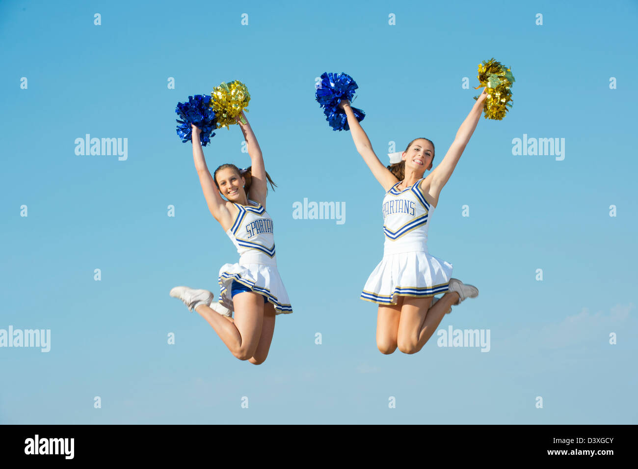Caucasian cheerleaders jumping in mid-air Stock Photo