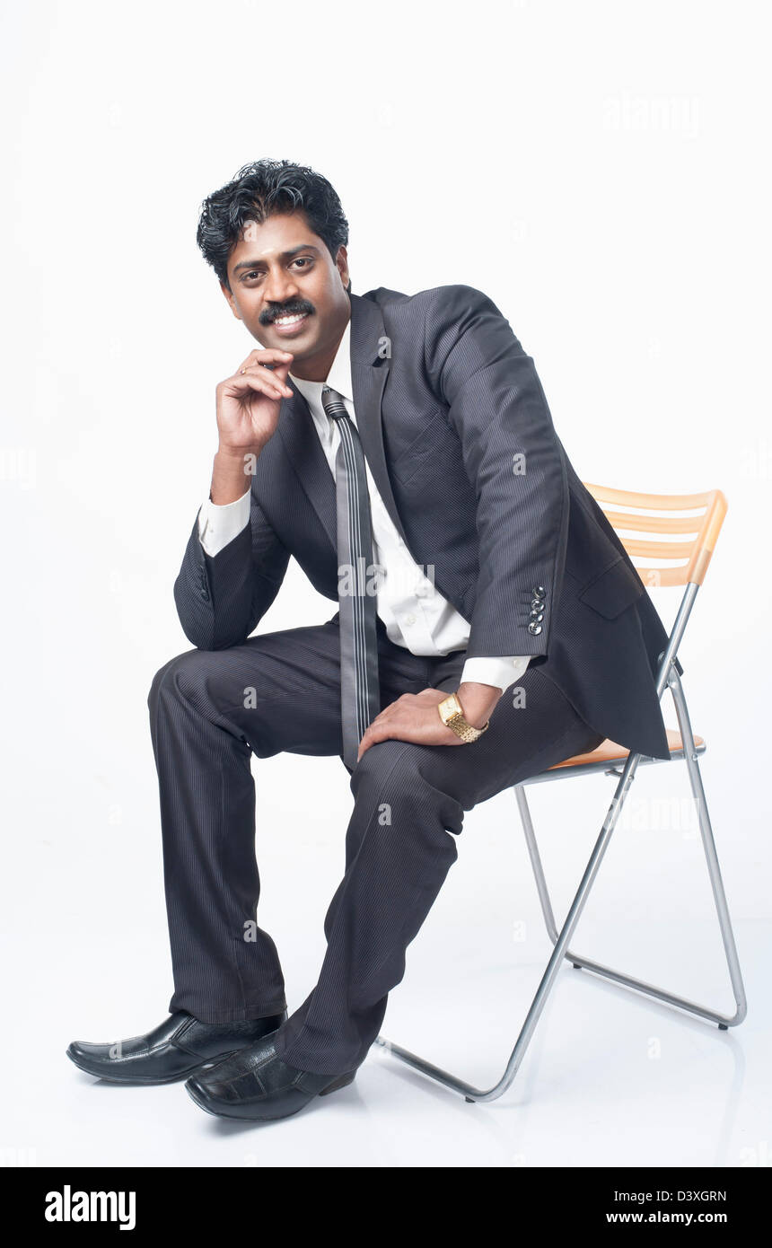 South Indian businessman sitting on a chair and smiling Stock Photo - Alamy