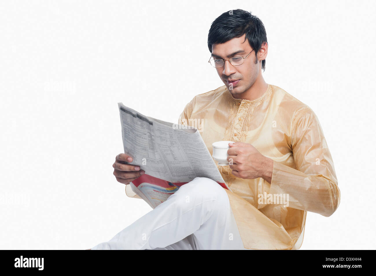 bengali man reading a newspaper and having tea D3XHH4