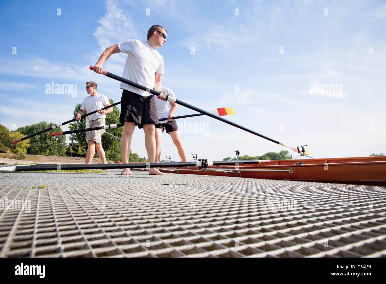 Teamwork Concept of Men Rowing Team Setting Paddles and Boat Stock Photo