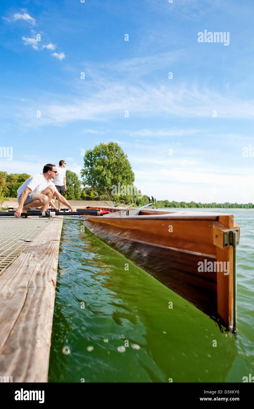 Teamwork Concept of Men Rowing Team Setting Paddles and Boat Stock