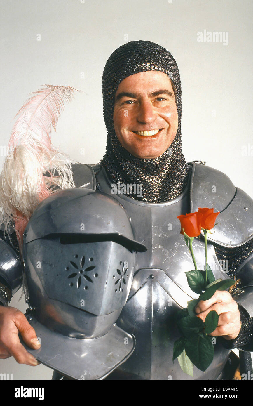 Knight in shinning Armor with a red rose, man smiling dressed in silver Armour holding a red rose Stock Photo