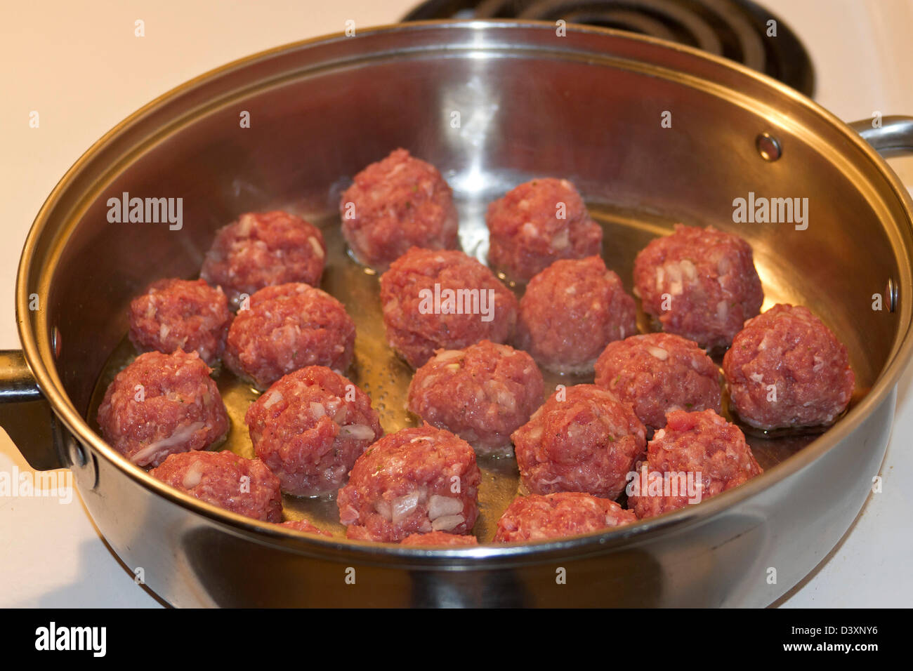 A frying pan with meatballs being fried in oil Stock Photo