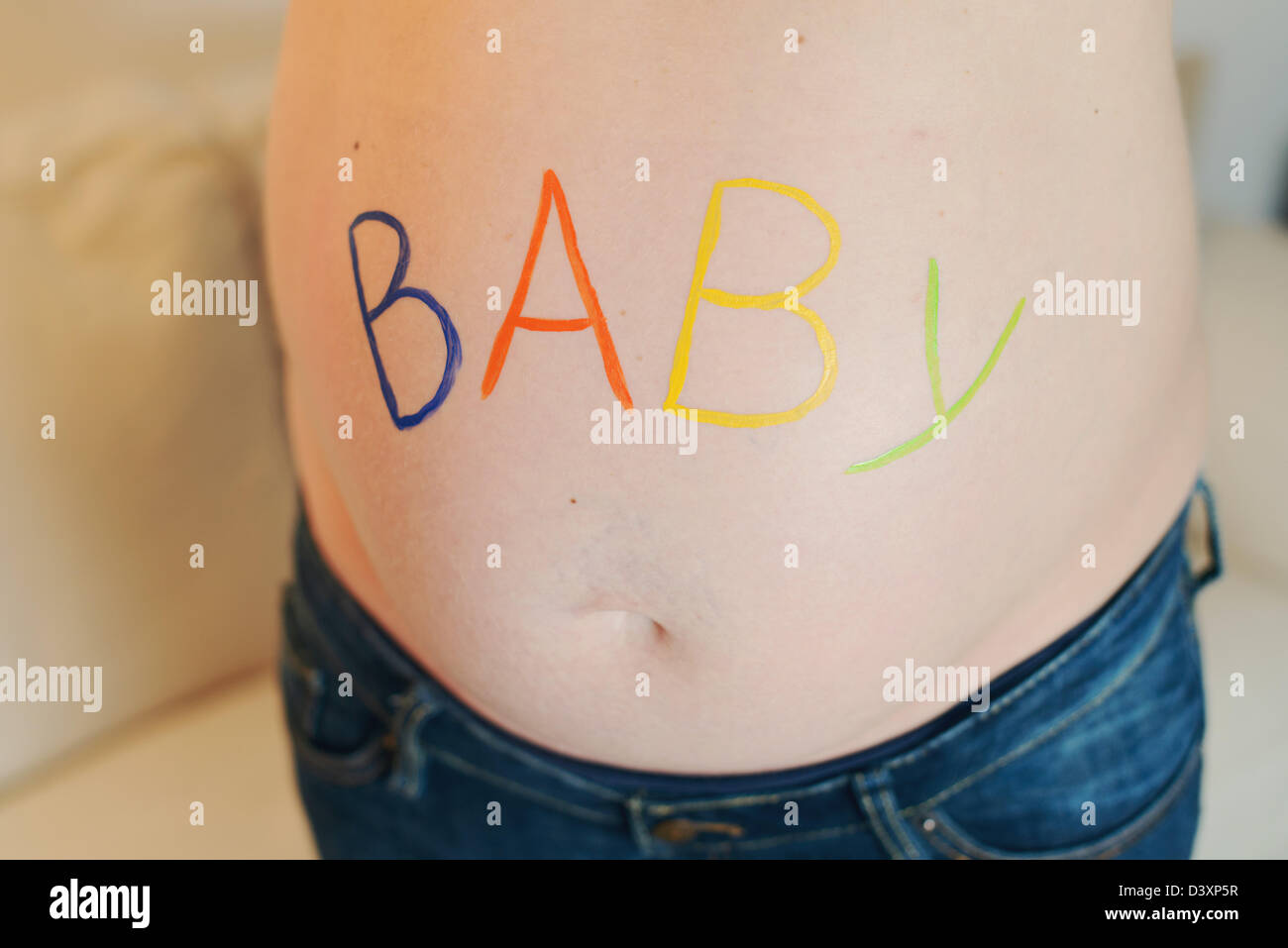 'Baby' is in colorful letters on the baby belly of a pregnant woman. Stock Photo