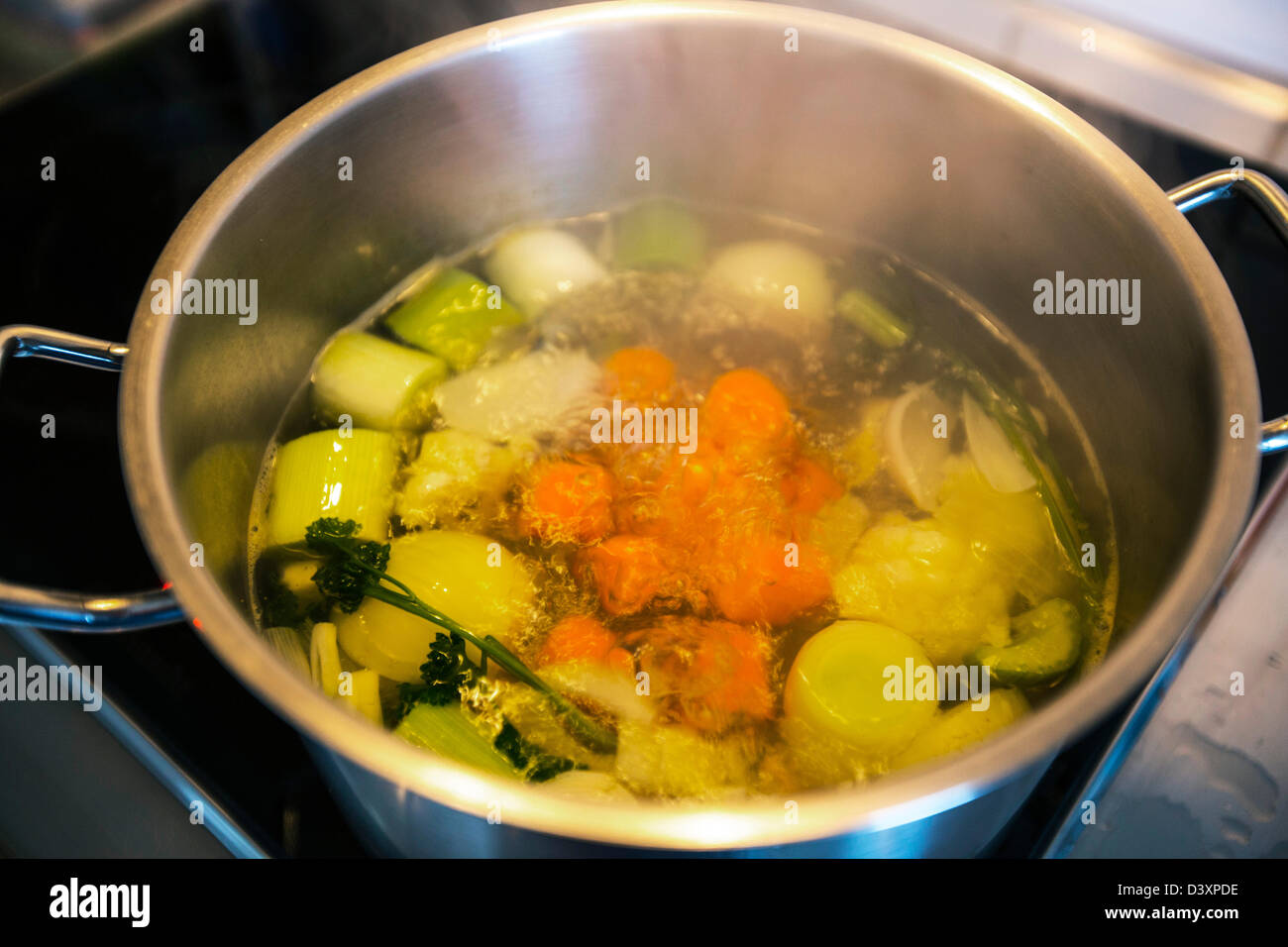 Different vegetables cooking in a pot for a vegetable soup. Stock Photo