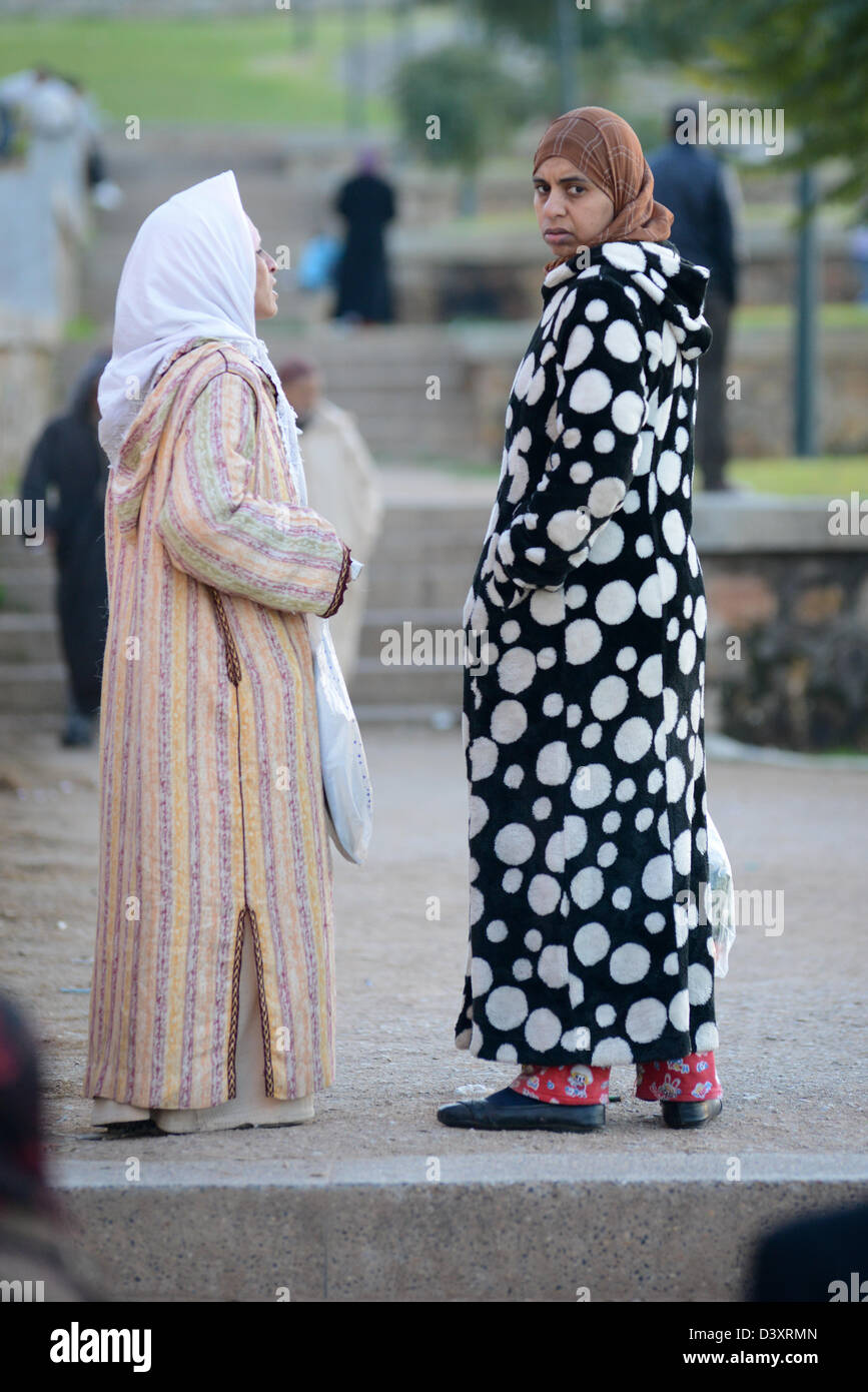 2 Moroccan women talking on the street, one is wearing a dressing gown and looking into the camera Stock Photo