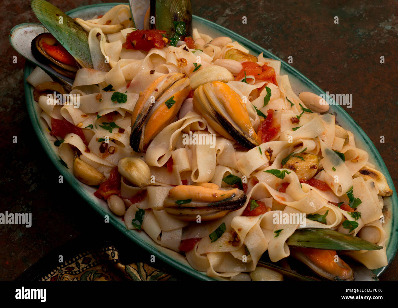A tagliatelle pasta platter with green mussels, garlic, cannelini beans and parsley. Stock Photo