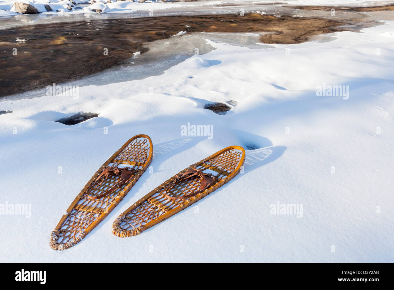 classic wooden Bear Paw snowshoes on the shore of partially frozen