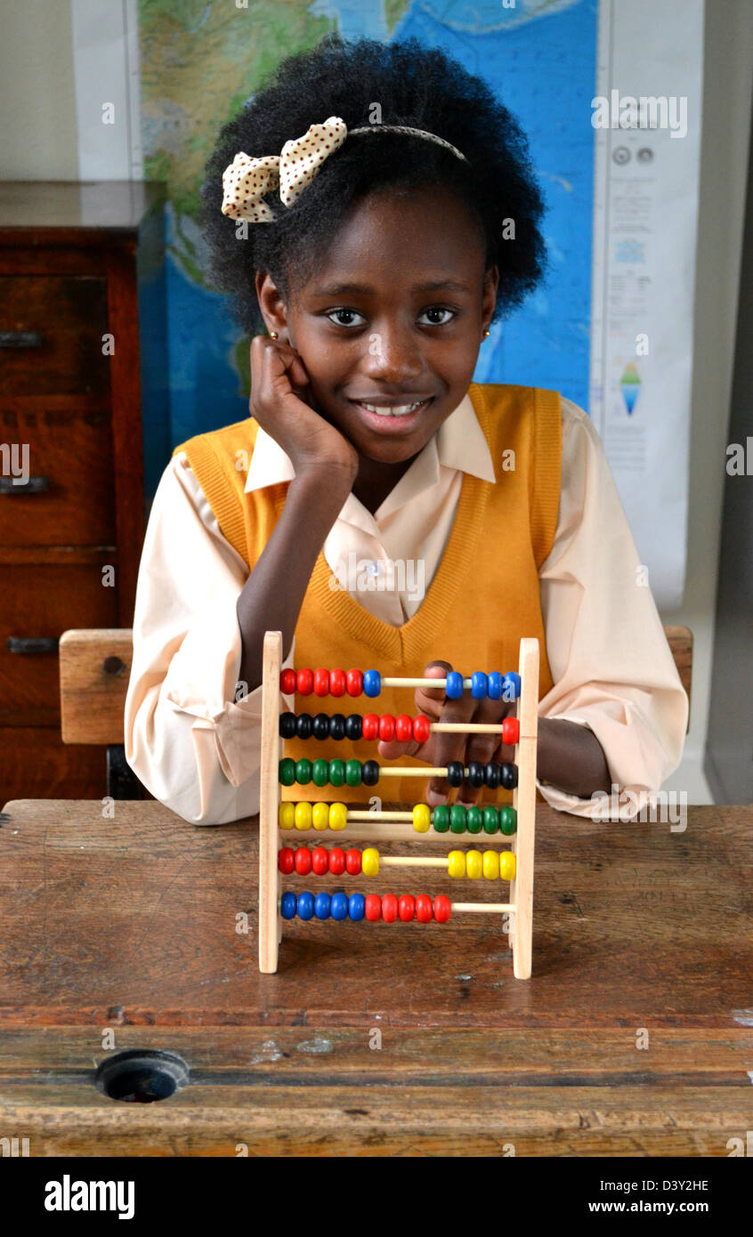 Pretty schoolgirl with an abacus on an old fashioned school desk Stock Photo