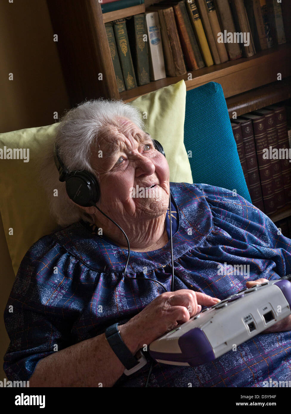 Elderly lady listening to a talking book with a tactile CD player designed for use by vulnerable hard of hearing, blind or visually impaired people Stock Photo
