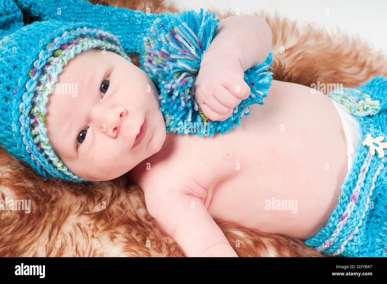 Newborn baby in long blue knitted hat with pom-pon Stock Photo - Alamy