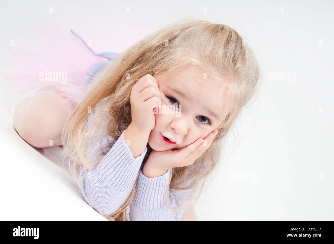 Cute blond girl sitting on the floor and watching on you Stock Photo ...