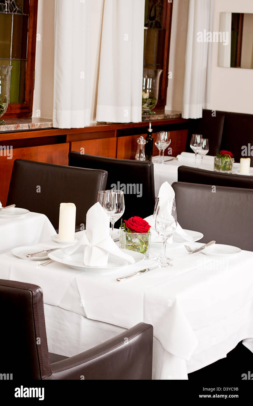tables in restaurant with white tablecloth and elegant dish and silverwear Stock Photo