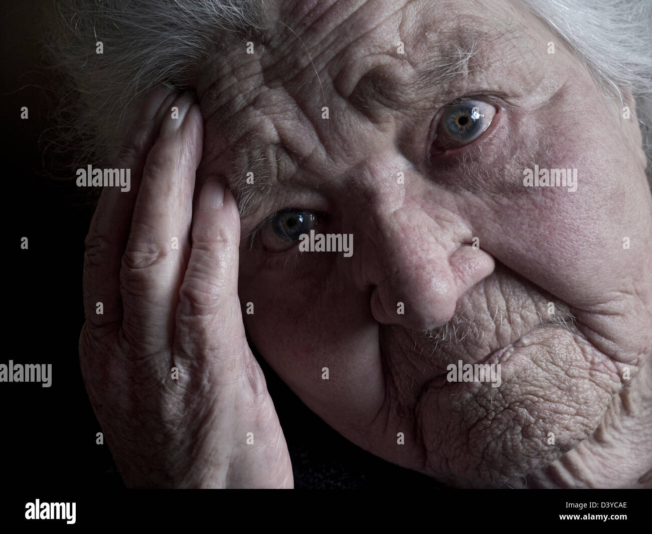 Elderly old age 100 years pensive lady close view face hand portrait looking directly at camera. Stock Photo