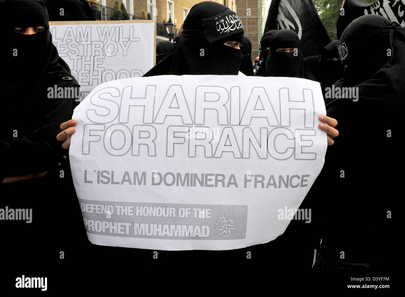 Women protesters wearing black burkas hold a sign reading 'Shariah for France' Stock Photo
