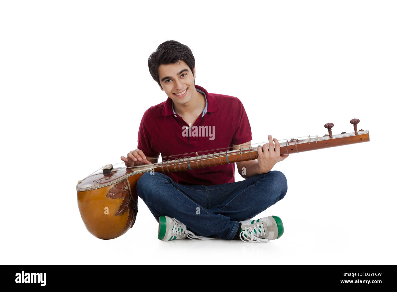 Happy man sitting on the floor and playing a sitar Stock Photo