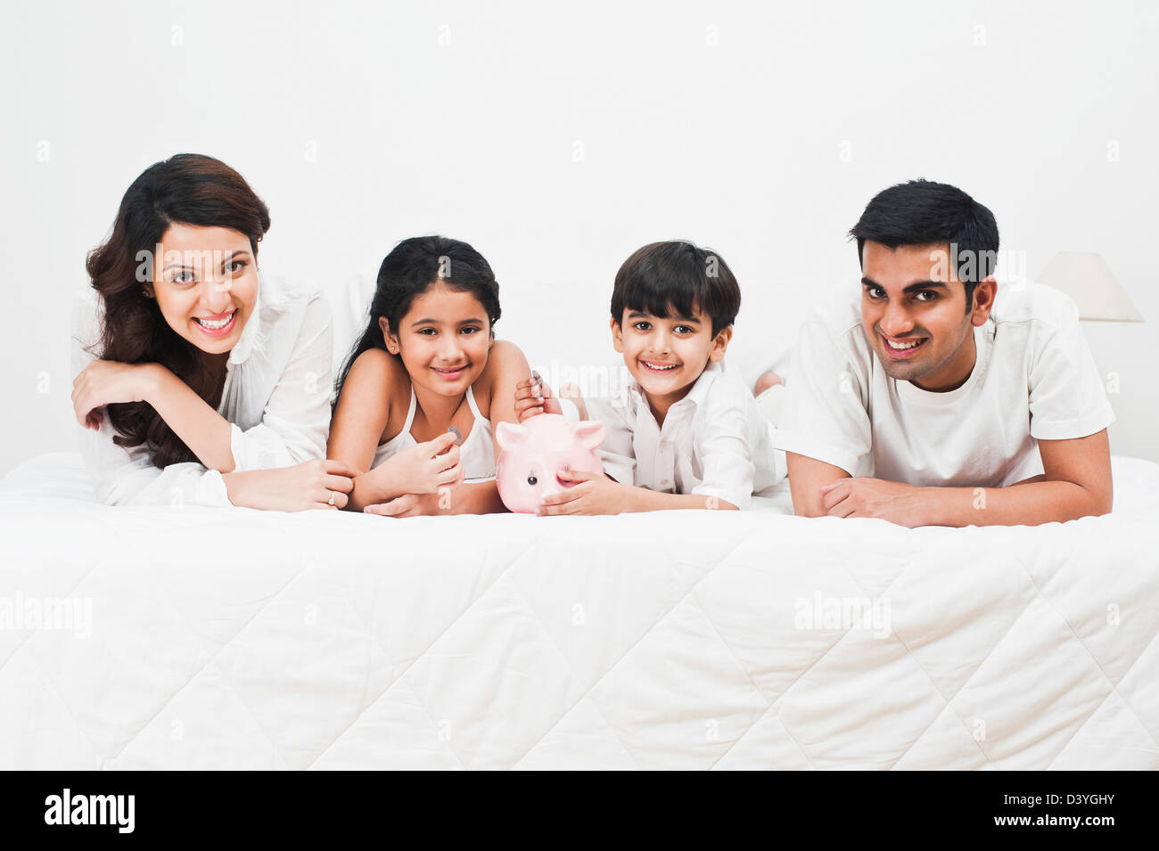 Happy family with a piggy bank on the bed Stock Photo - Alamy