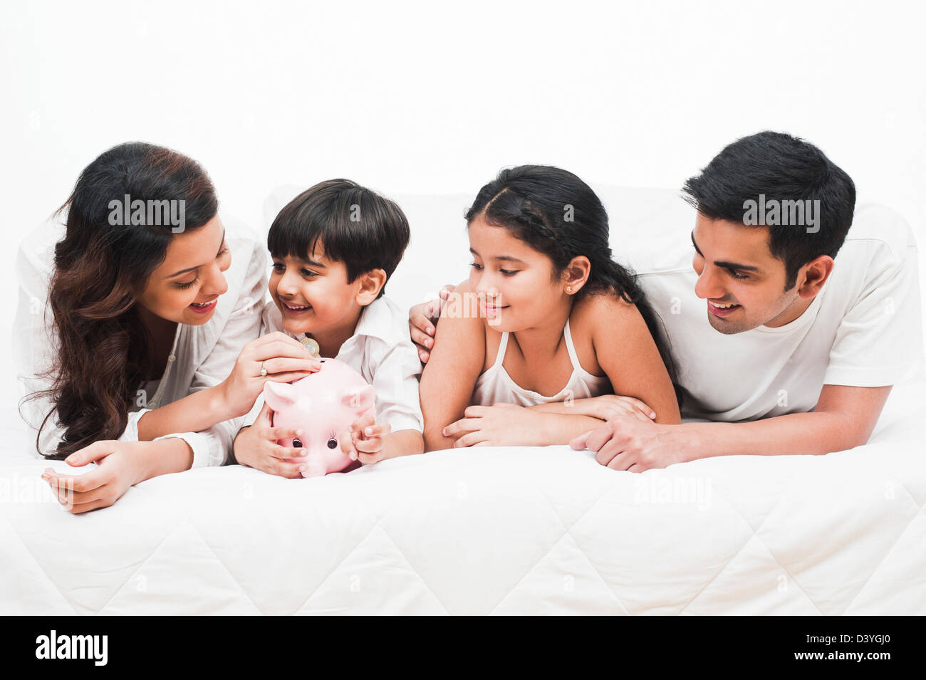 Happy family with a piggy bank on the bed Stock Photo - Alamy