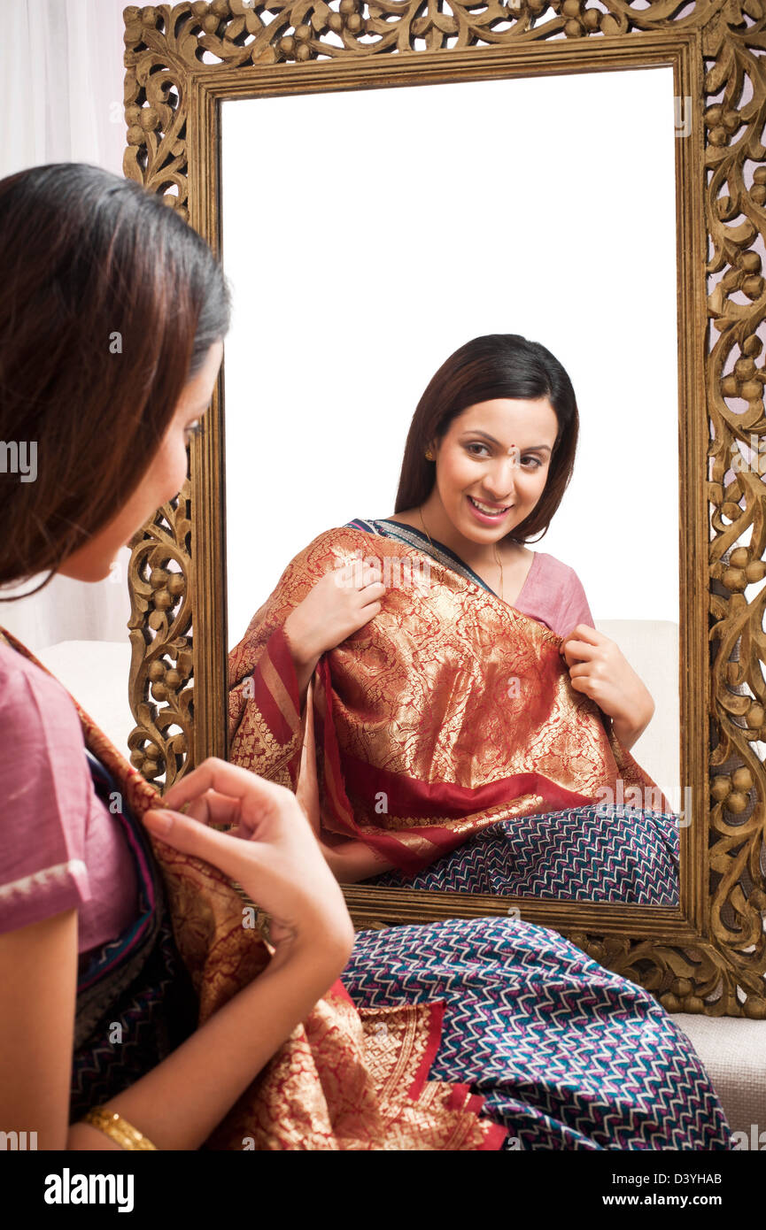 Reflection of a woman in mirror trying a sari on herself Stock Photo