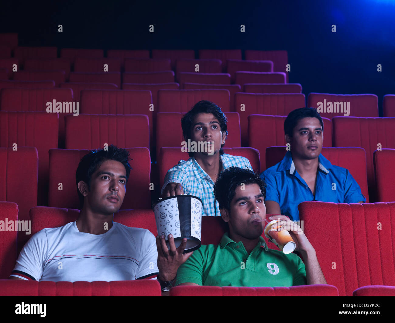 Youngsters enjoying movie with popcorns in a cinema hall Stock Photo