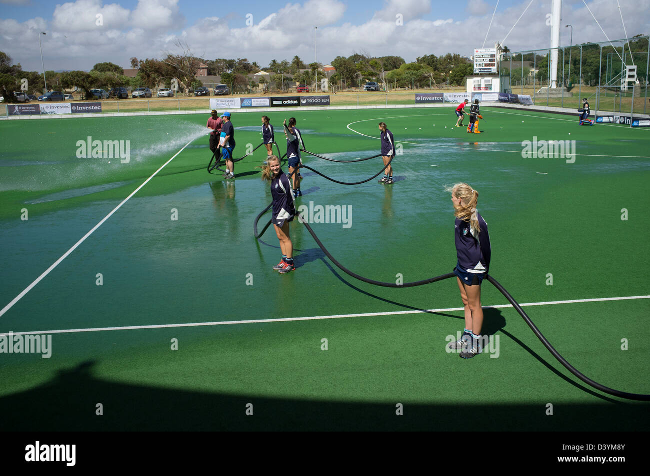 Young hockey players assist the ground staff in watering the pitch pre match at Hartleyvale Stadium Cape Town S Africa Stock Photo
