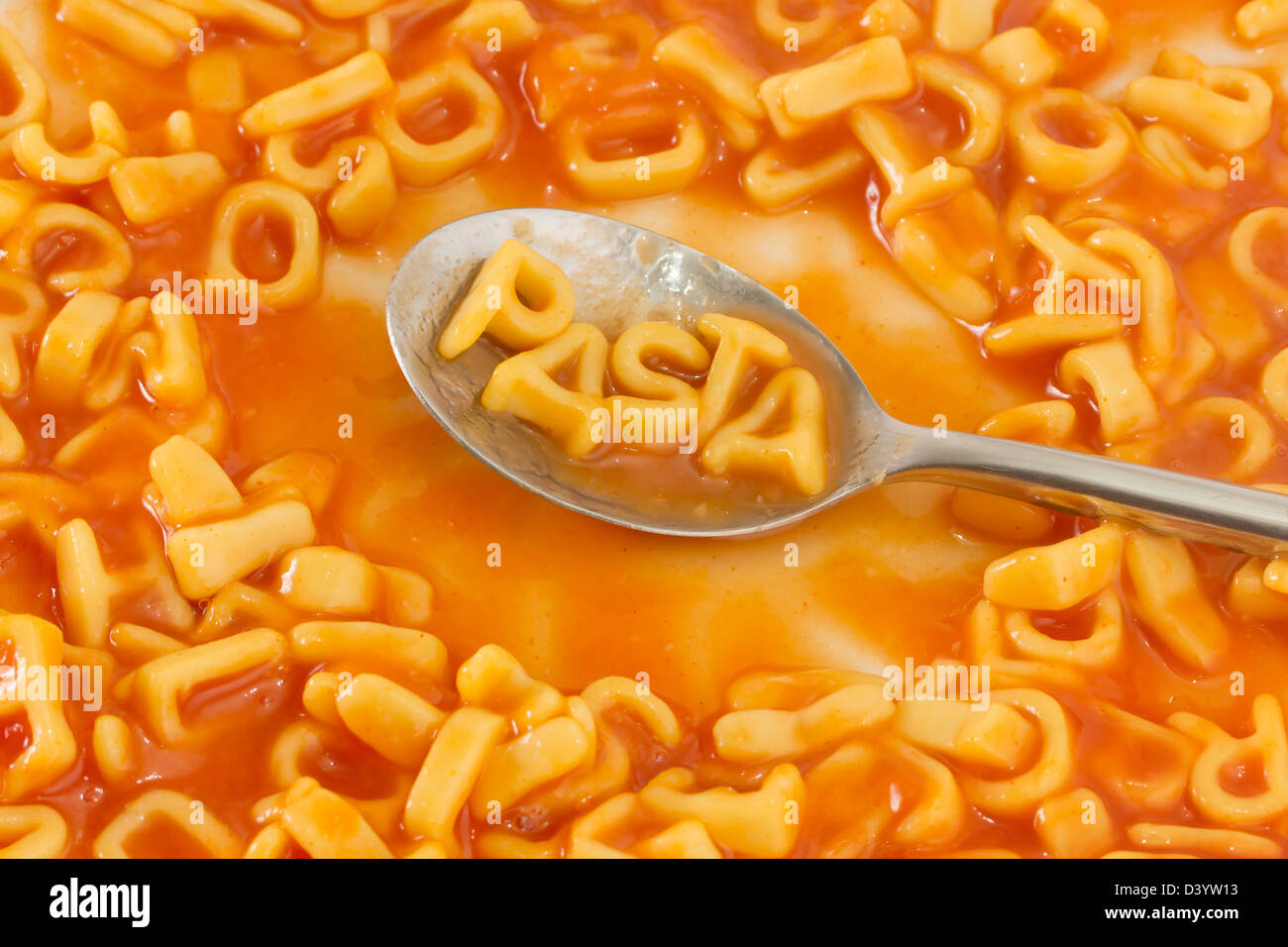 Pasta shaped letters spelling the word PASTA on a spoon within pasta shaped letters in tomato sauce Stock Photo