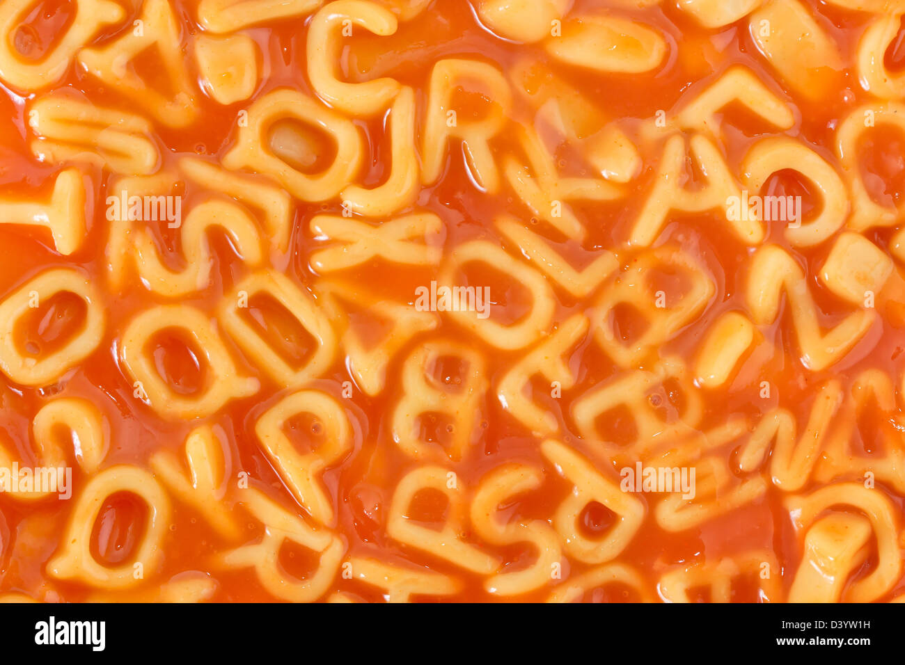Background of pasta shaped alphabet letters in a tomato sauce Stock Photo