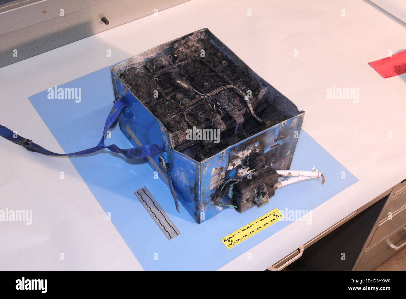 NTSB photos of the burned auxiliary power unit battery from a JAL Boeing 787 that caught fire on January 7, 2013 at Boston's Logan International Airport. The dimensions of the battery are 19x13.2x10.2 inches and it weighs approximately 63 pounds Stock Photo