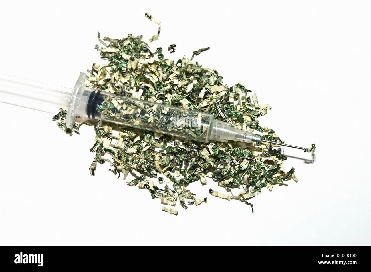 Shredded money with a syringe full. Concept or metaphor for cost of drugs, health, wasting money on drugs, medical plans, etc. Stock Photo
