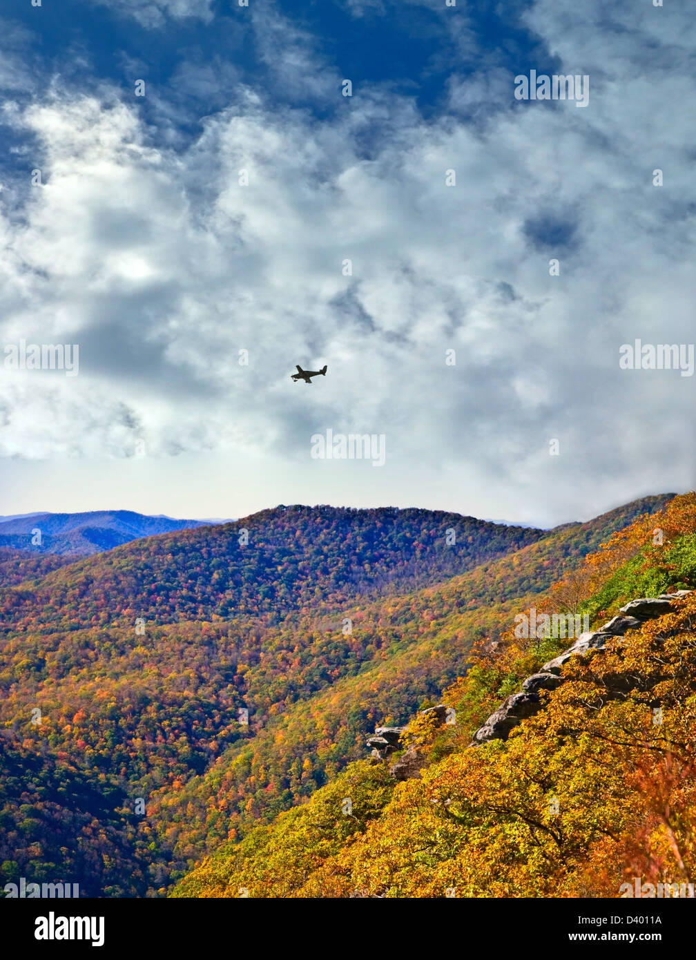 Long distance view of mountains in the fall with a small airplane flying over. Stock Photo