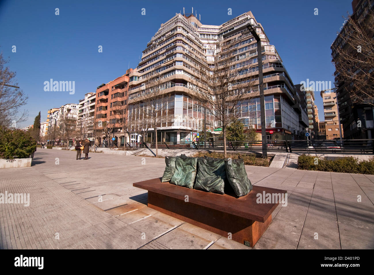 Bank with cushions of bronze and singular building , known as the pyramid,in the background. Granada. Spain Stock Photo
