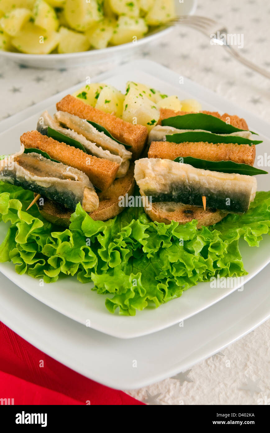 Skewers of fried eel and fried bread, and parsely potatoes on a lettuce bed, Christmas food, Italy, Italian cooking Stock Photo