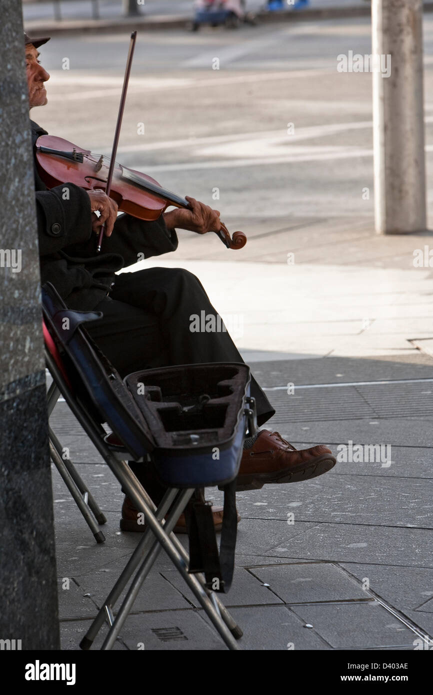 Old violinist playing for a few coins while contemplates the people passing. Granada, Spain Stock Photo
