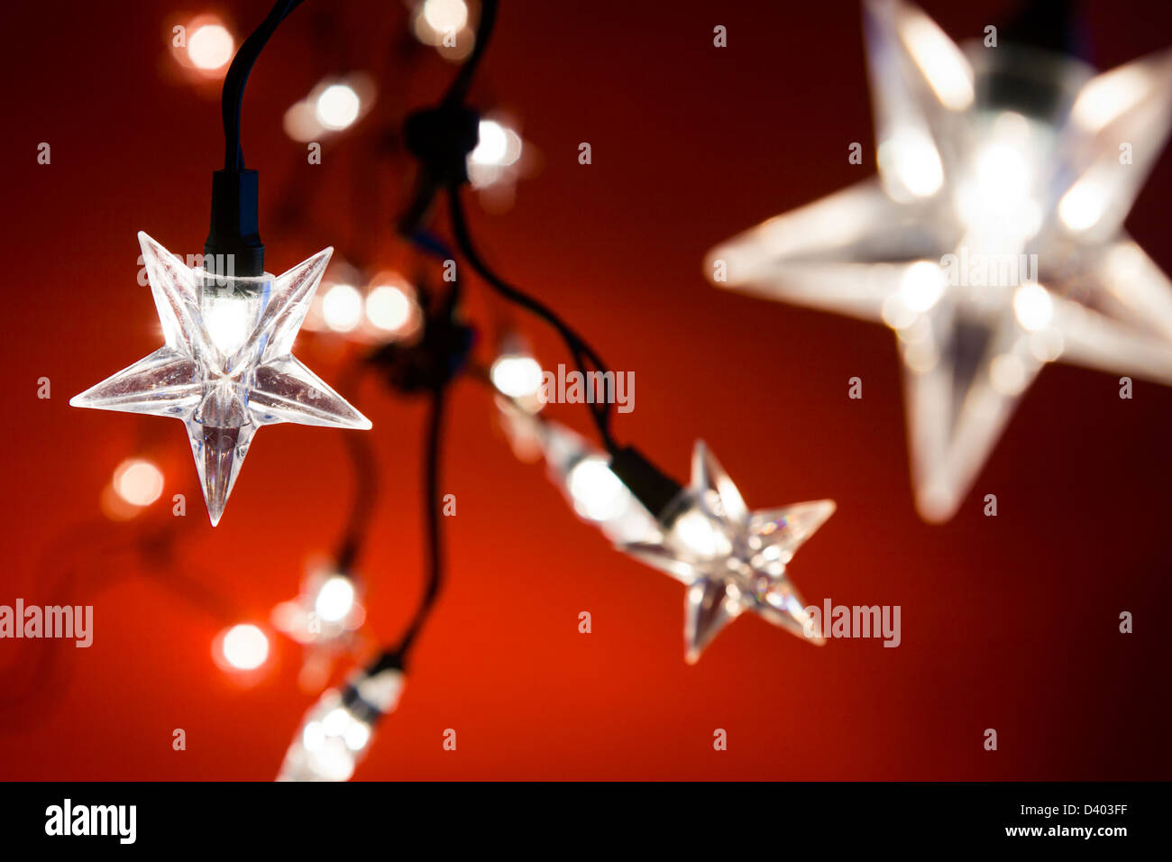 Line of star shaped Christmas lights against a red background, narrow depth of field. Stock Photo