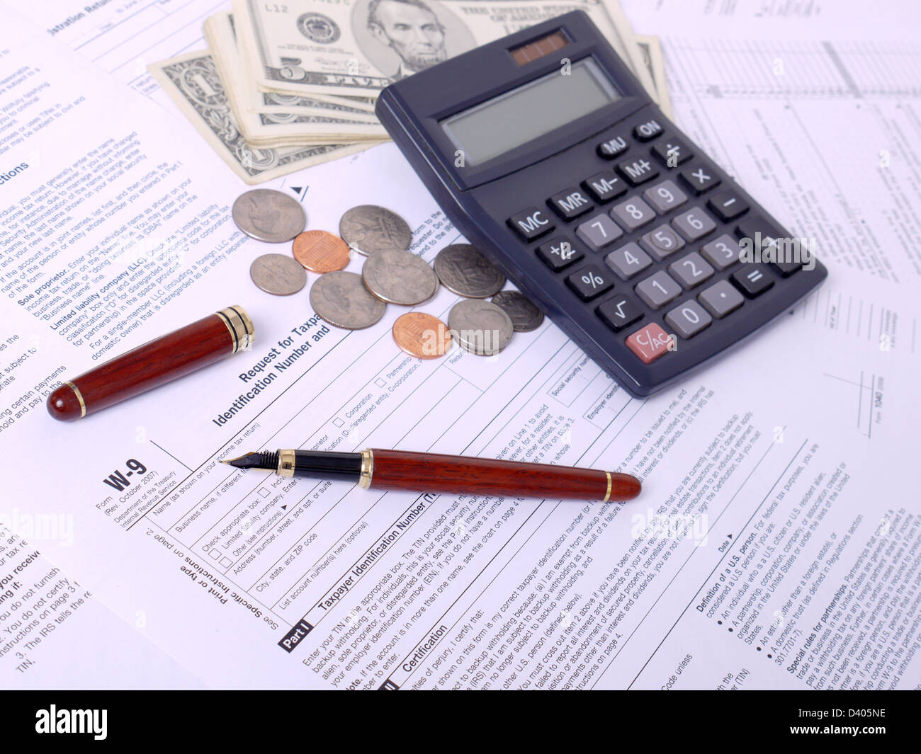 Calculator, ink pen and american dollars on W-9 income tax forms Stock Photo