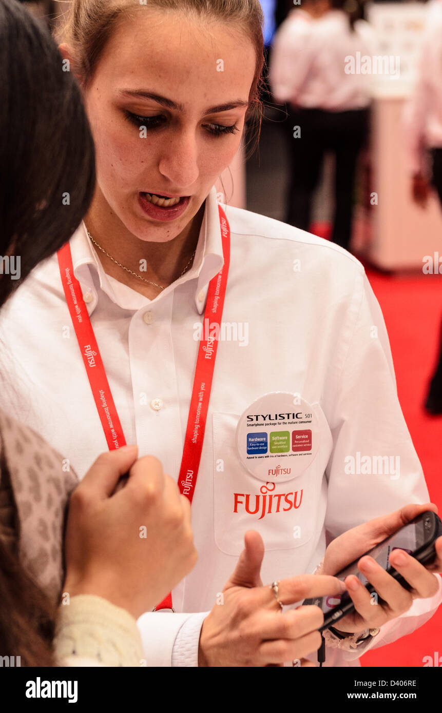 Barcelona, Spain. 27th February 2013: An employee demonstrates the  Fujitsu Stylistic S01, a mobile device for the generation 55+, to a visitor, at the Mobile World Congress 2013. Stock Photo