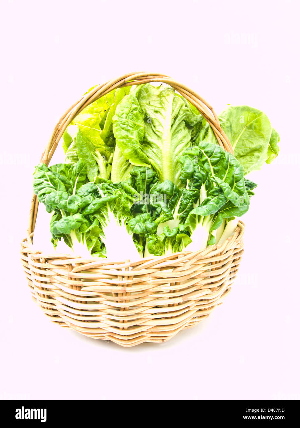Fresh baby bok choy and cos salad in rattan basket isolated on white background Stock Photo